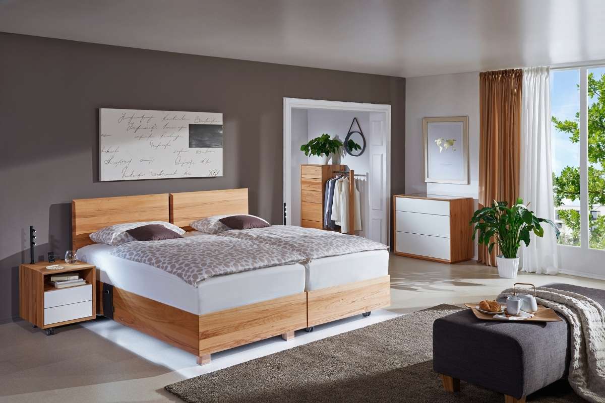 Seniorenbett mit Holzrahmen und integrierter Aufstehhilfe in warmem Licht