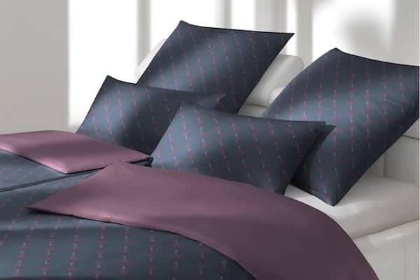 Feine Bettwäsche in gedeckten Farben auf Boxspringbett arrangiert (WebP, komprimiert)