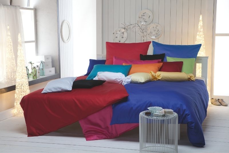 Gefaltete Bettwäsche in sanften Cremetönen auf einer Bank