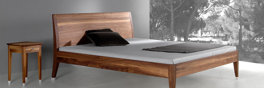 Breites Holzbett mit Sideboard und ruhiger Farbwelt im Schlafzimmer