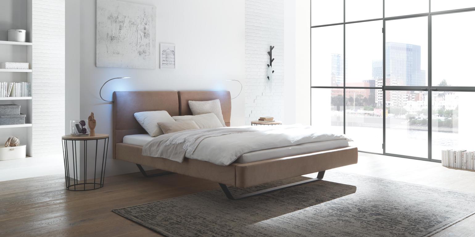 Modernes Polsterbett mit strukturierter Wand und Lichtstimmung